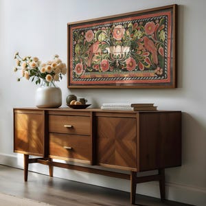 Puede incluir: Un aparador de madera de estilo moderno de mediados de siglo con dos cajones y dos puertas. El aparador tiene un patr&oacute;n geom&eacute;trico en las puertas y est&aacute; hecho de una madera marr&oacute;n rica. Una obra de arte enmarcada con un dise&ntilde;o floral y dos p&aacute;jaros est&aacute; colgada en la pared sobre el aparador.