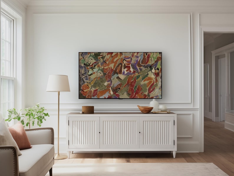 May include: A living room with a white cabinet, topped with decorative items, and a large abstract painting. A floor lamp with a beige shade stands beside a cream sofa with a rust-coloured cushion. The room has wooden flooring.
