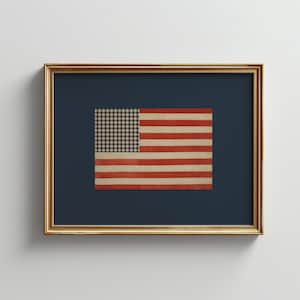 Könnte beinhalten: Gerahmtes Kunstwerk mit einer amerikanischen Flagge im Vintage-Stil. Das Flaggen-Design umfasst rote und weiße Streifen mit einem karierten Muster in der oberen linken Ecke. Das Kunstwerk ist vor einem dunkelblauen Hintergrund platziert und in einem goldfarbenen Rahmen.