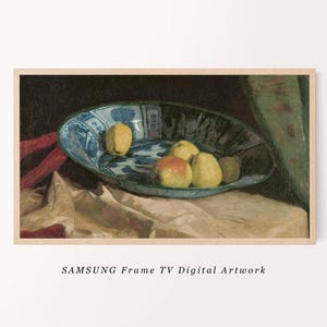 May include: A blue and white ceramic bowl filled with yellow and red apples. The bowl is sitting on a white tablecloth with a red cloth in the background.