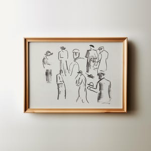 Op de afbeelding: Een ingelijst kunstwerk met een houtskoolschets van verschillende figuren met hoeden en jassen. Het kunstwerk bevindt zich in een lichtgekleurde lijst en is op een witte muur gemonteerd. De figuren zijn afgebeeld met eenvoudige lijnen en schaduwen.