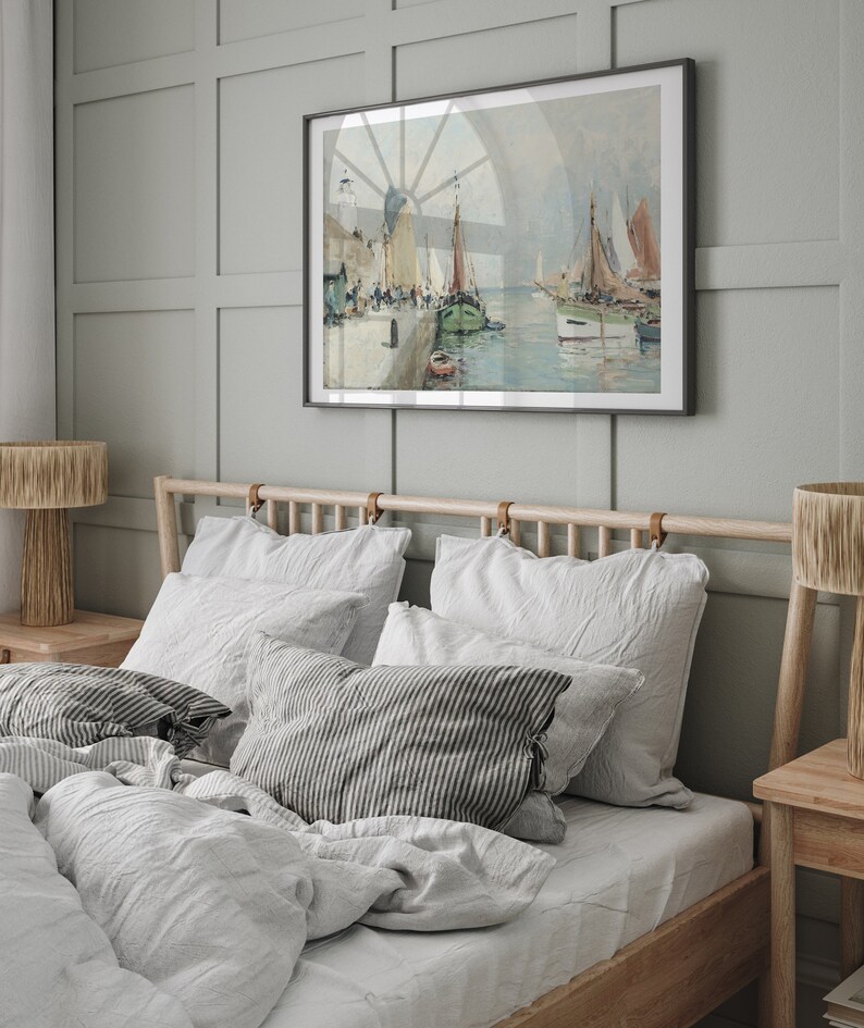 K&ouml;nnte beinhalten: Ein Schlafzimmer mit einem Holzbettgestell und wei&szlig;er Bettw&auml;sche aus Leinen. Das Kopfteil hat Lederriemen. &Uuml;ber dem Bett h&auml;ngt ein gerahmtes Gem&auml;lde einer Seest&uuml;ck. Das Gem&auml;lde zeigt eine Hafenszene mit Booten und einem Leuchtturm.
