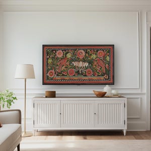 Puede incluir: Un armario blanco con tres puertas se encuentra frente a una pared blanca. Una obra de arte enmarcada con fondo negro y dise&ntilde;os florales y de p&aacute;jaros coloridos cuelga sobre el armario. Una l&aacute;mpara de pie con pantalla blanca se encuentra a la izquierda del armario.