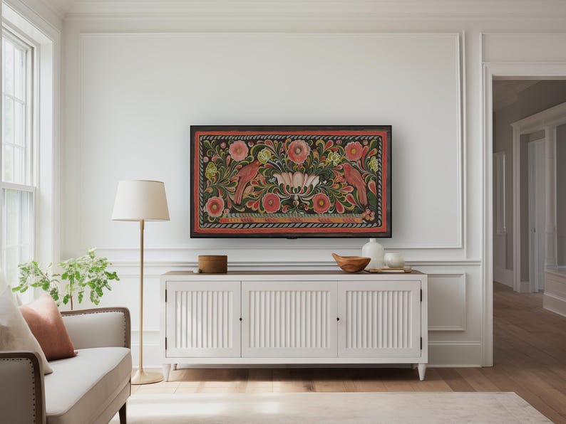 Puede incluir: Un armario blanco con tres puertas se encuentra frente a una pared blanca. Una obra de arte enmarcada con fondo negro y dise&ntilde;os florales y de p&aacute;jaros coloridos cuelga sobre el armario. Una l&aacute;mpara de pie con pantalla blanca se encuentra a la izquierda del armario.