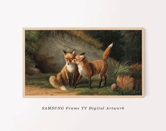 May include: A rectangular digital artwork for a Samsung Frame TV featuring two red foxes in a forest setting. One fox sits near a rocky den while the other stands beside it. The scene includes green grass, dark trees, and a light wood frame border.