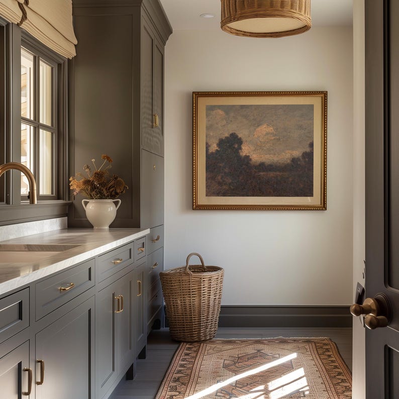 May include: A gray kitchen with white countertops and cabinets. A wicker laundry basket sits in the corner of the room. A framed painting of a landscape hangs on the wall.