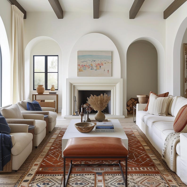 May include: A living room with a white sofa, two armchairs, a coffee table, and a rug with a geometric pattern. The room has a fireplace with a painting above it, and arched doorways leading to other rooms.