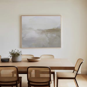 Peut inclure: Une table &agrave; manger en bois clair avec six chaises en cannage. La table est dress&eacute;e avec un bol et un vase avec de la verdure. Un tableau abstrait encadr&eacute; est accroch&eacute; au mur derri&egrave;re la table.