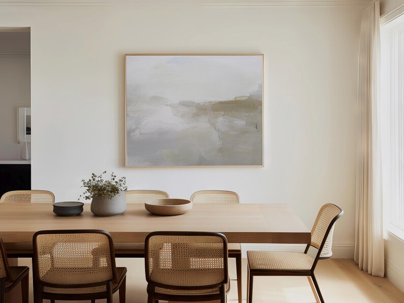 Peut inclure: Une table &agrave; manger en bois clair avec six chaises en cannage. La table est dress&eacute;e avec un bol et un vase avec de la verdure. Un tableau abstrait encadr&eacute; est accroch&eacute; au mur derri&egrave;re la table.
