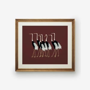 May include: A framed print of a line of seven black and white cranes with red beaks walking in a single file line on a maroon background.