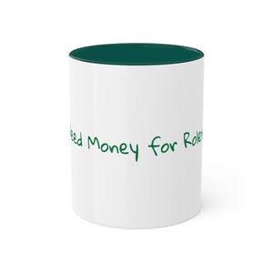 May include: White ceramic mug with a green rim and the text "Need money for Rolex" written in green.