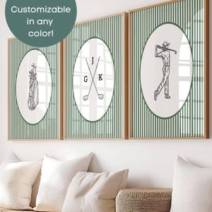 May include: Three framed golf-themed prints. Each print features a white oval with a golf-related illustration against a green and white striped background. The prints are in wooden frames. Text in the upper left corner says "Customizable in any color!"