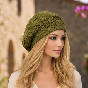 May include: An olive green crochet beret featuring a textured, open-work pattern on the crown and a ribbed, fitted band. The hat is crafted from yarn with a visible knit structure, displaying a slouchy silhouette that sits comfortably on the head.