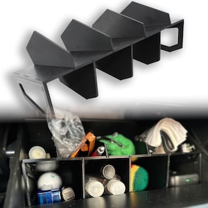 Könnte beinhalten: Schwarzer Auto-Organizer aus Kunststoff mit mehreren Fächern. Der Organizer ist für die Aufbewahrung im Handschuhfach oder in der Konsole eines Autos konzipiert und bietet Stauraum für verschiedene Gegenstände. Das Bild zeigt den Organizer gefüllt mit Gegenständen wie Golfbällen, Stiften und anderen kleinen Objekten.