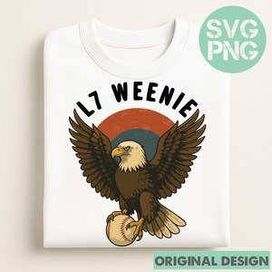 Può includere: Felpa bianca con una grafica di un'aquila calva che tiene una palla da baseball. L'aquila è marrone e bianca con le ali spiegate, su un cerchio retrò rosso e blu. Il testo "L7 WEENIE" è sopra l'aquila.