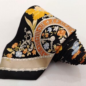 May include: Black silk tie with a floral and clock face design. The tie features orange, yellow, and blue flowers, with a beige border. The clock face has Roman numerals and a key design.