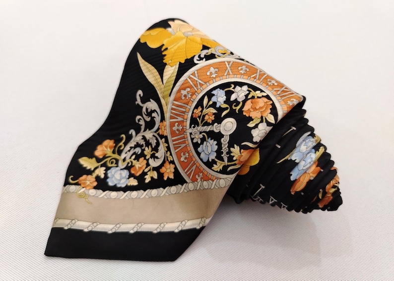 May include: Black silk tie with a floral and clock face design. The tie features orange, yellow, and blue flowers, with a beige border. The clock face has Roman numerals and a key design.