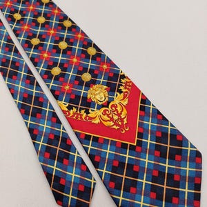 Pode incluir: Uma gravata de seda azul e vermelha xadrez com um design estampado em dourado e vermelho que apresenta uma cabeça de Medusa dourada.