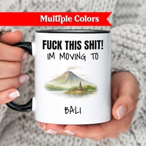 Puede incluir: Taza de cerámica blanca con asa y borde negros, con el texto "FUCK THIS SHIT! I'M MOVING TO BALI" en negro. La taza también muestra una ilustración escénica de una montaña y una isla.