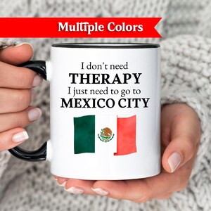 May include: White ceramic mug with a black handle and rim, displaying the text "I don't need THERAPY I just need to go to MEXICO CITY" and the Mexican flag. A red banner at the top reads "Multiple Colors".