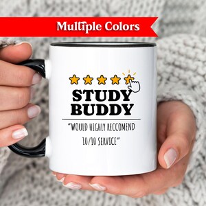 Puede incluir: Taza de cerámica blanca con asa y borde negros, con el texto "STUDY BUDDY" en letras negras. El diseño incluye cinco estrellas doradas y la frase "WOULD HIGHLY RECOMMEND 10/10 SERVICE".