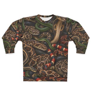 May include: A long-sleeve sweatshirt featuring an all-over print of various snakes, including a prominent cobra with a flared hood, green snakes, and snakes with red, black, and yellow bands. The design covers the entire garment in a dense pattern.