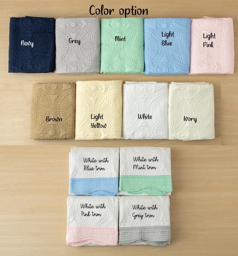 May include: A variety of folded blankets in various colors, including navy, grey, mint, light blue, and light pink. Additional colors are brown, light yellow, white, and ivory. The image also shows white blankets with colored trim in blue, mint, pink, and grey.