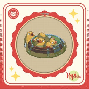 May include: A cross-stitch pattern featuring a group of yellow ducklings in a wooden tub, surrounded by water. The pattern is framed in a red and white hoop.