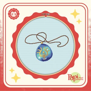 Puede incluir: Un colgante azul y dorado con un diseño de remolino cuelga de un cordón marrón sobre un fondo blanco. El colgante está en un aro de bordado rojo. La imagen está rodeada por un borde de lunares rojos y blancos.