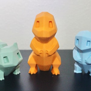 May include: Three low-poly 3D printed figurines of Pokemon characters. The figures are in a light blue, orange, and green color scheme.