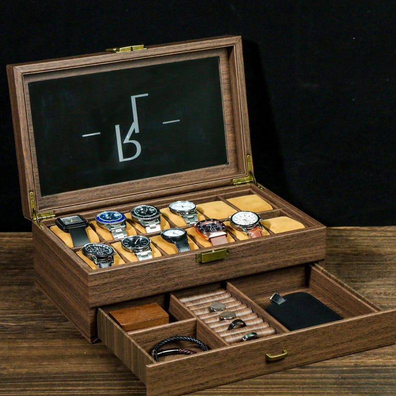 May include: A wooden watch box with a glass top and a drawer. The box has a black interior and is filled with watches. The drawer has a brown interior and is filled with rings and other jewelry.