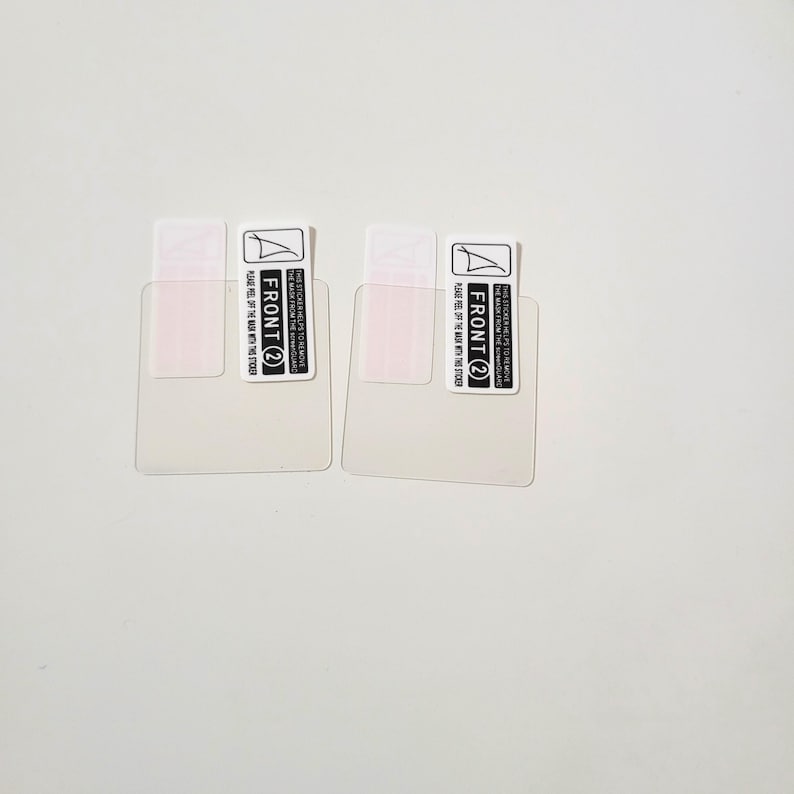 May include: Two clear screen protectors with attached labels. Each label reads "FRONT 2" and includes instructions to peel off the mask. The protectors are rectangular with rounded corners, designed for a device screen.