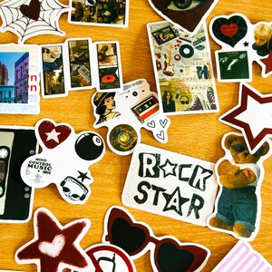 以下が含まれることがあります： クモの巣、テディベア、星、カセットテープ、音符、そして「Rock Star」の文字など、さまざまなデザインのカラフルなステッカーのコレクションです。