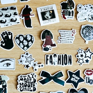 May include: A collection of black and white stickers with various designs, including stars, eyes, a heart with faces, a disco ball, a bow, and text that reads "Stay Wild Moon Child", "Downtown Girl", "Fashion", "Welcome to Earth", "I'm thinking phases and how I fill spaces and the places I want to dance in", and "Star Girl".