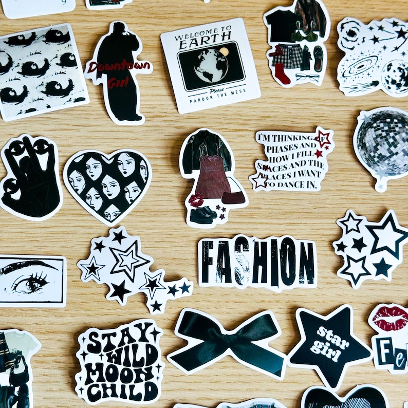 May include: A collection of black and white stickers with various designs, including stars, eyes, a heart with faces, a disco ball, a bow, and text that reads "Stay Wild Moon Child", "Downtown Girl", "Fashion", "Welcome to Earth", "I'm thinking phases and how I fill spaces and the places I want to dance in", and "Star Girl".