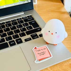 May include: A pink sticky note with the text "Note to self: Your best is enough!!" on a silver laptop with a white chick figurine.