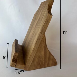 May include: A wooden book stand with a natural finish. It measures 11 inches tall, 9 inches wide, and 8 inches long. The stand has a 1.5 inch wide base.