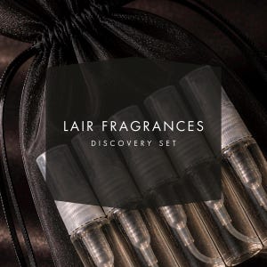 May include: A black drawstring bag containing several small, clear spray bottles. The bottles are arranged in a row and have black caps. The text "LAIR FRAGRANCES DISCOVERY SET" is overlaid on the image.