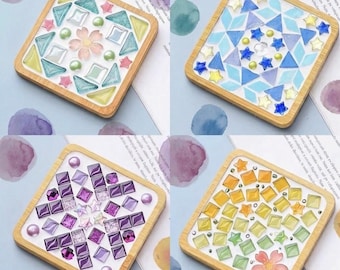Pode incluir: Quatro porta-copos quadrados de madeira com designs de mosaico. Um tem formas de vidro pastel e uma flor, um tem estrelas de vidro azul e amarelo, um tem peças de vidro quadradas roxas e um tem vidro amarelo e verde com uma flor.
