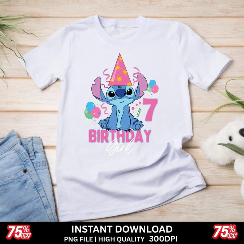 May include: White t-shirt featuring a blue cartoon character wearing a party hat, with the number 7 and the words "BIRTHDAY Girl" in pink. The design includes balloons and confetti. The shirt is displayed on a light wooden surface.