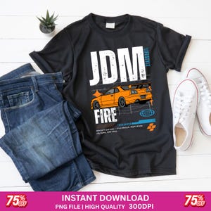 May include: Black t-shirt with a graphic of an orange sports car and the words "JDM FIRE" in white. The shirt is styled with blue jeans and white sneakers, suggesting a streetwear theme.