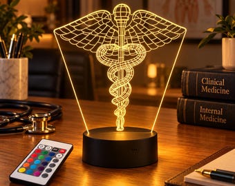 May include: A 3D LED lamp featuring a glowing yellow caduceus symbol on a flat acrylic panel. The lamp has a circular black base and comes with a multi-colored remote control. The design displays a staff with two wings and two snakes.