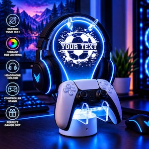 May include: A black gaming headset rests on a circular stand featuring a glowing blue light-up panel with a soccer ball graphic and the text YOUR TEXT. A white game controller sits on the integrated clear acrylic base below the headset.