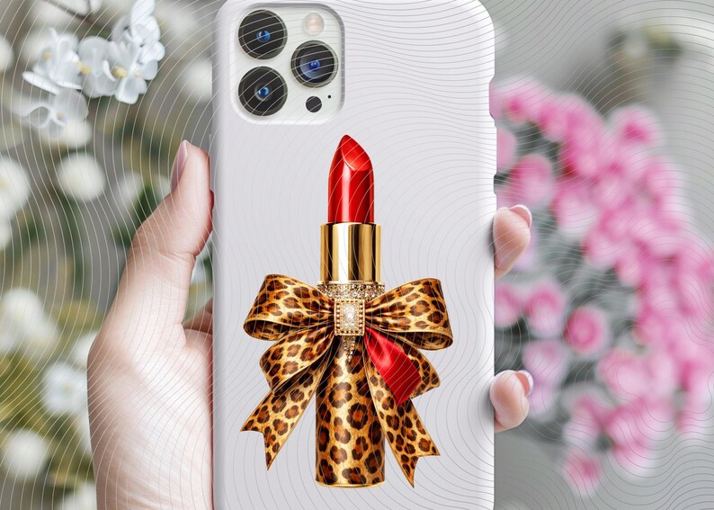 May include: A white smartphone case featuring a central graphic of a bright red lipstick tube. The base of the lipstick is wrapped in a large, detailed leopard print bow with a small, rectangular, clear crystal embellishment at the center.