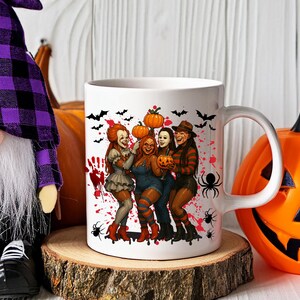 K&ouml;nnte beinhalten: Wei&szlig;e Keramiktasse mit einem Halloween-Design mit vier kost&uuml;mierten Figuren, K&uuml;rbissen, Flederm&auml;usen und Spinnen. Das Design umfasst rote Spritzer. Die Tasse hat einen wei&szlig;en Henkel und ist f&uuml;r Hei&szlig;getr&auml;nke geeignet.