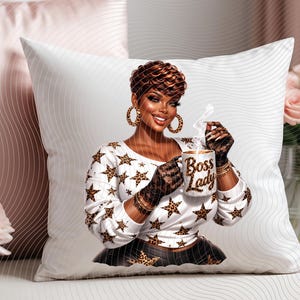 May include: White decorative pillow featuring an illustration of a woman holding a mug. The woman is wearing a white top with star and leopard print accents. The mug reads "Boss Lady". The pillow is on a white surface.