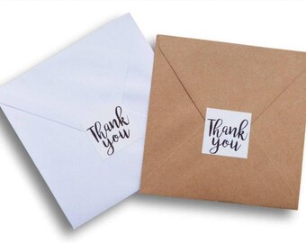 May include: Two white envelopes with "Thank you" stickers on them. One envelope is on top of the other.