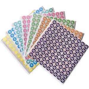 Może przedstawiać: Zbiór etykiet z rozmiarami w różnych kolorach, w tym żółtym, niebieskim, różowym, zielonym, pomarańczowym i fioletowym. Każda etykieta zawiera oznaczenie rozmiaru, takie jak XS, S, M, L, XL, XXL i XXXL. Etykiety są ułożone w stosy.