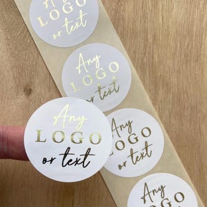 May include: Roll of white round stickers with gold foil lettering that says "Any LOGO or text".