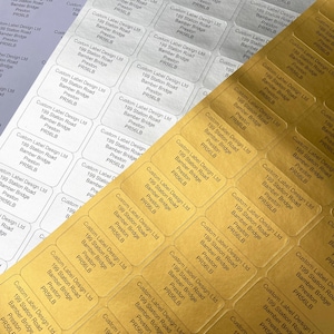 Può includere: Primo piano di etichette adesive rettangolari argentate e dorate. Ogni etichetta, disposta a griglia, mostra il testo "Custom Label Design Ltd, 199 Station Road, Bamber Bridge, Preston, PR56LB".